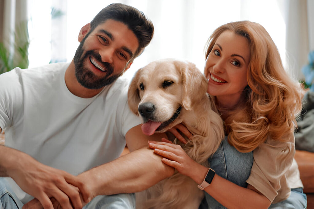 Young couple playing and hugging their pet labrador dog